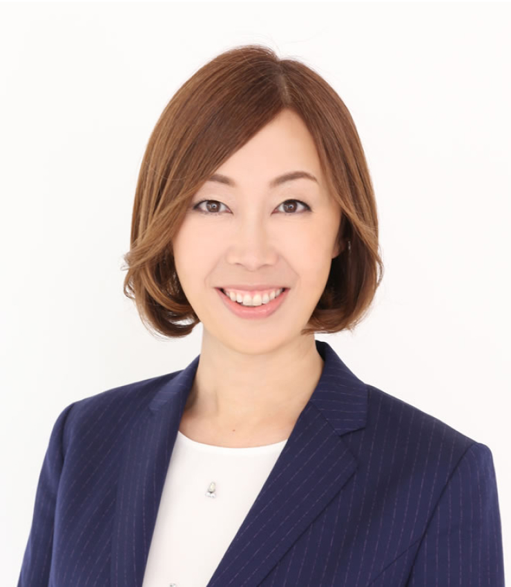 代表の本人画像。ブロンド色で長めショートの女性。紺色のスーツを着て笑顔で正面を向いている。